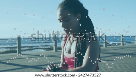 Image of statistics and graphs over woman using smartwatch on promenade by the sea. digital interface global sport and performance concept digitallygenerated image.