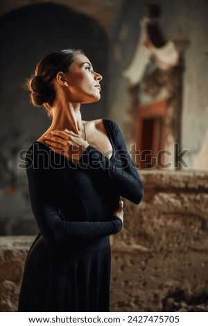 Portrait of an gracious prima ballerina standing in vintage abandoned interior and performing choreography alone. An elegant ballet dancer expressing her art in rustic building. Copy space. Royalty-Free Stock Photo #2427475705