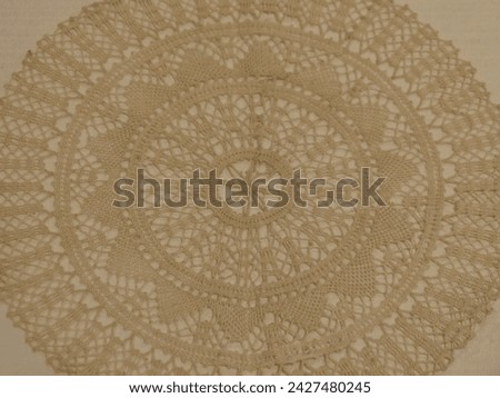ecru mat crotch doilie over beige background Royalty-Free Stock Photo #2427480245