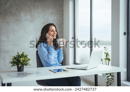 Business woman, laptop and smile for phone, communication or reading at the office. Happy female employee event planner checking email, social media or post on smartphone and computer at workplace