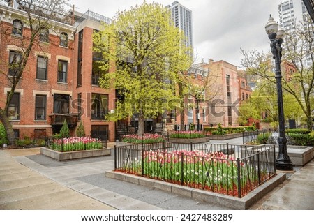Small square with flower beds and a fountain surrounded by brick residentail buildings in old town Chicago on a cloudy spring day Royalty-Free Stock Photo #2427483289