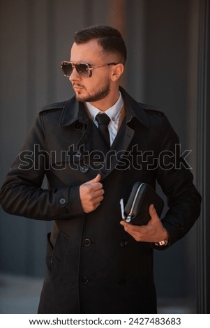 Portrait of a young fashionable man wearing elegant black coat . High quality photo