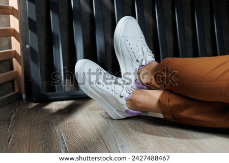 White leather sneakers on women's legs. Women's legs in comfortable casual sneakers