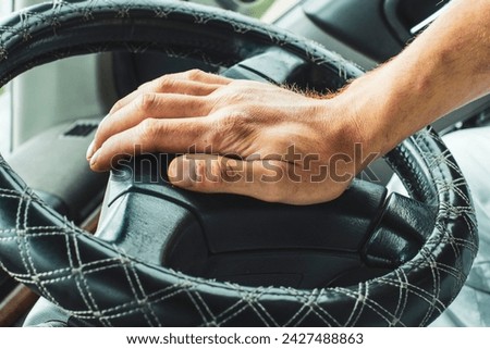 Male hand honking the car horn, man driving vehicle and beeping, front and back background blurred Royalty-Free Stock Photo #2427488863