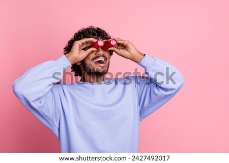 Photo of positive funny guy wear blue trendy clothes look far away binocular empty space poster isolated on pink color background