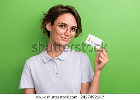 Photo of adorable lovely girl wear stylish clothes hand demonstrate plastic bank card isolated on green color background