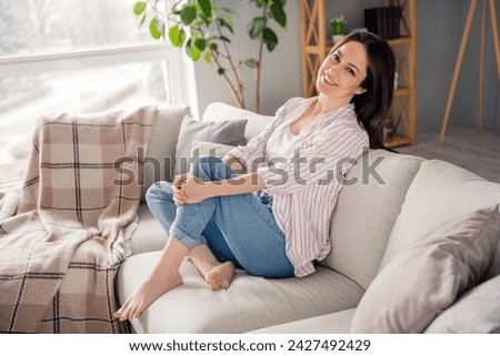 Full length profile photo of adorable satisfied glad person sit barefoot couch free time chill house inside Royalty-Free Stock Photo #2427492429