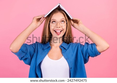 Photo of funky carefree lady dressed blue shirt fooling stick out holding book head looking up empty space isolated pink color background