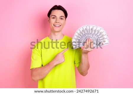 Photo portrait of pretty teen man hold point money fan dressed stylish yellow clothes isolated on pink color background