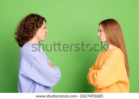 Profile portrait of two unsatisfied capricious people folded hands sullen face look each other isolated on green color background