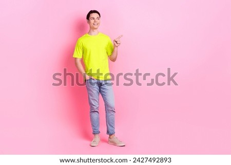 Full length photo of dreamy funny guy wear green t-shirt pointing finger looking empty space isolated pink color background