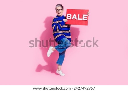 Full body photo of attractive pensioner woman hold shopping sale plate wear trendy blue striped clothes isolated on pink color background