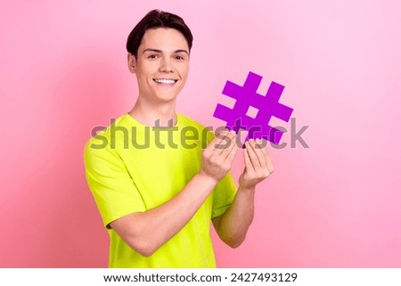 Photo portrait of nice teen man hold hashtag influencer dressed stylish yellow clothes isolated on pink color background