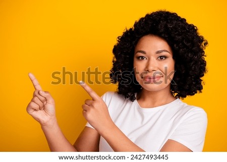 Photo of girlish woman with perming coiffure dressed white t-shirt indicating at promo empty space isolated on yellow color background
