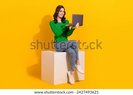 Full body length photo of brunette business lady sitting podium at video call with laptop in coworking isolated on yellow color background