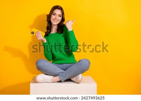Full body photo of woman green jumper with smartphone follow trends in  point finger empty space isolated on yellow color background