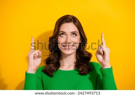 Photo of pretty girl toothy smile look direct fingers up empty space offer isolated on yellow color background