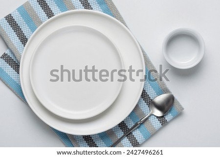 White empty plate with spoon and napkin on white background