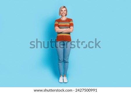 Full length photo of adorable positive woman dressed knitwear t-shirt jeans holding arms crossed isolated on blue color background