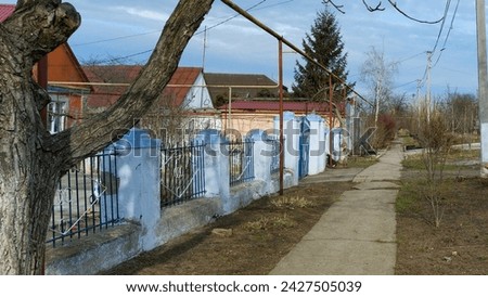 old fence in the village, stone pillars, iron lattice, sky, fir tree, road, tree. High quality photo
