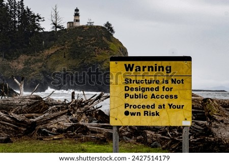A Warning sign in front of a pile of drift wood warning that the structure is not designed for Public Access. Proceed at your own risk.