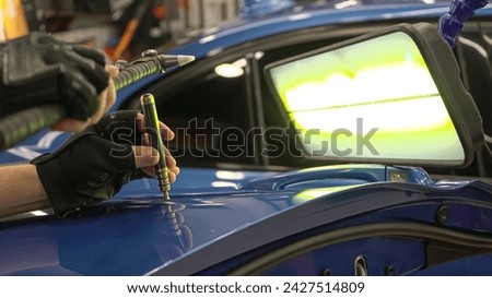 Process of paintless dent repair on car body. The mechanic at the auto shop with tools to repair dents in car body. Body repair. PDR. A specialist repairs a dent on the car body without painting. Royalty-Free Stock Photo #2427514809