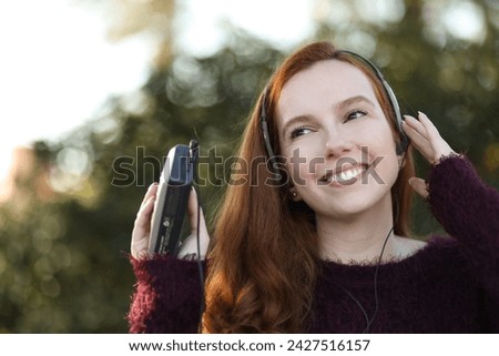 Beautiful young woman smiles while listening to music with her old player Royalty-Free Stock Photo #2427516157