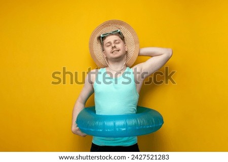 young guy in the summer on vacation with an inflatable swimming ring and a straw hat sunbathes and smiles