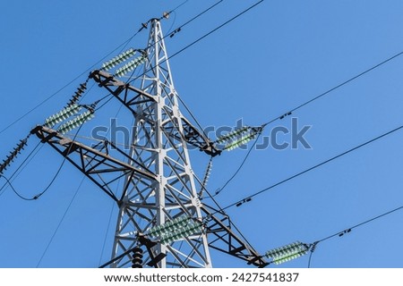 It's close up view of High voltage electric tower in a sunny day. It is blue sky background. It is photo of electric tower Royalty-Free Stock Photo #2427541837