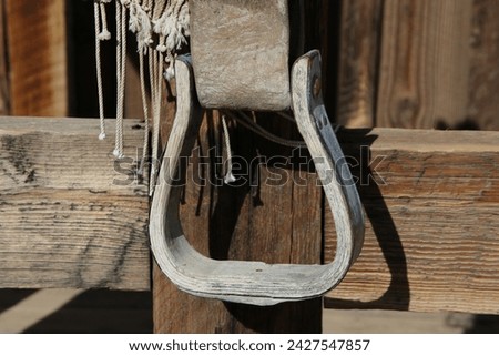 An old wood and metal stirrup on an old western style saddle.