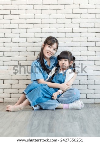 Happy asian beautiful young mother and cute daughter little girl smiling posing hugging on white brick wall background studio portrait Mother's Day love family parenthood childhood concept.