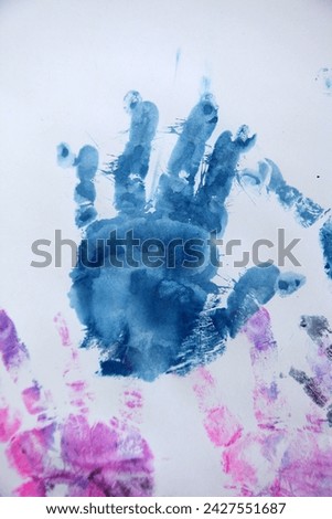 Indoor close up photo view visual of a handprint of a kid child infant children baby young made with blue painting on a white paper sheet for fun creative activity during school time or home time