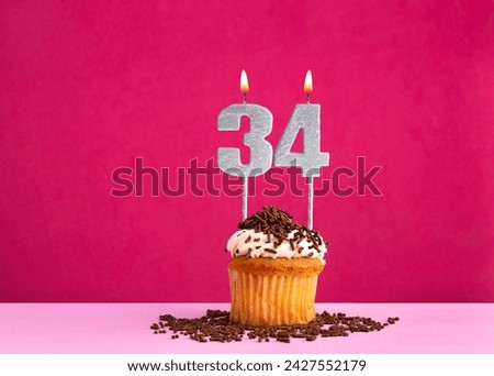Birthday celebration with candle number 34 - Chocolate cupcake on pink background