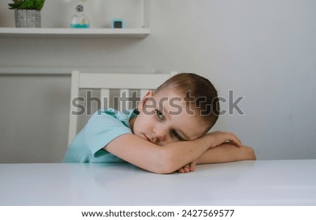 One sad, tired boy, holding his head while sitting at table in his room. Anxiety and stress. Concept of bullying, depressive stress or disappointment, sadness Royalty-Free Stock Photo #2427569577