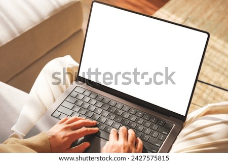 Mockup image of a woman working and typing on laptop computer with blank screen while sitting on sofa at home
