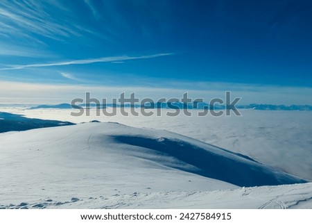 Scenic view of fog covered Lavanttal valley surrounded by snow capped mountain peaks Karawanks and Julian Alps seen from top of Grosser Speikkogel, Kor Alps, Lavanttal Alps, Carinthia Styria, Austria Royalty-Free Stock Photo #2427584915