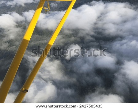 Picture of broken clouds taken from above them from a small private airplane with part of the yellow plane in the picture for framing.