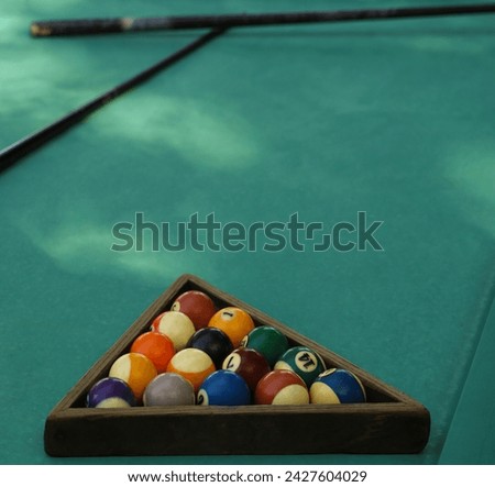 Bright billiard balls and a cue ball for billiards, in a wooden triangle on the playing table. Next to cue stick. Preparation for the tournament and competition.entertainment, leisure and recreation