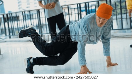 Caucasian hipster doing head spin while surrounded by multicultural friends. Hip-hop dancer practicing break dancing or preparing for street dancing. B-boy dance concept. Outdoor sport 2024. Endeavor.
