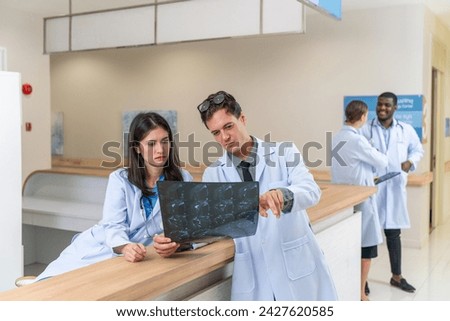Doctors working together looking at a x-ray film scan discussing solution and idea for a medical case in a hospital Royalty-Free Stock Photo #2427620585