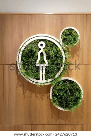 A women's restroom sign in the mall adorned with beautiful plant decorations