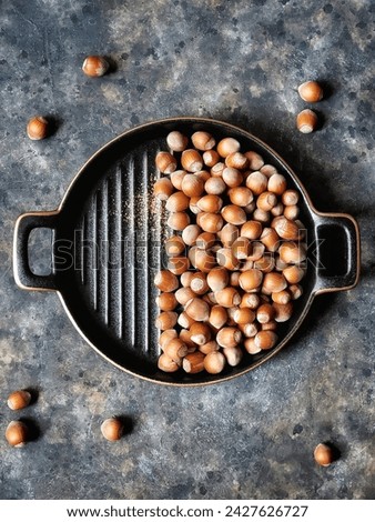 Top view on Hazelnuts in retro plate on black concrete old table. Healthy nuts. Still life with wild nut in trendy Rustic style.