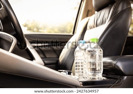 Plastic bottle of water placed on car seat and exposed to sun in sunny day,bottle of drinking water in car,sunlight,very hot,heating temperature,cause danger if parked in the sunshine for a long time Royalty-Free Stock Photo #2427634957