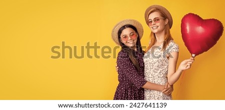 Mother and daughter kid banner, copy space, isolated background. smiling mom and daughter hold love heart balloon on yellow background.