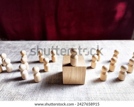 Wooden toy doll on high pedestal and many other figures below. Concept of leadership, which is not available to everyone. Victory and the winner. Talent, Recruitment employee and Successful business Royalty-Free Stock Photo #2427658915
