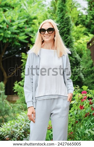 Smiling woman in tracksuit stands in the garden