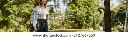 Header with smiling teenage girl with skateboard walking in park Royalty-Free Stock Photo #2427667269