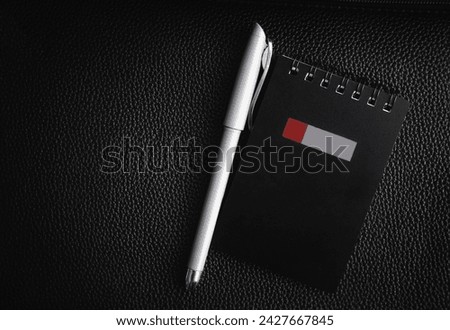 Notepad and pen on a black background, with a place for writing. Stock photo of the notebook