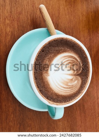 Close up shot of hot latte coffee with latte art in a ceramic white cup and saucer on white background with clipping path. Hot milk art coffee on a wooden table, A cup of hot coffee with latte art on.