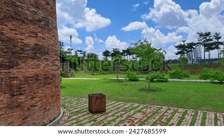 Background of A red brick building with a view of grass, plants and clear sky during the day